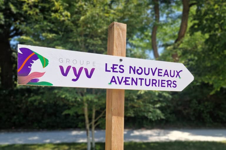 Flèche directionnelle en bois indiquant le nom de l'événement "les nouveaux aventuriers" vers la droite